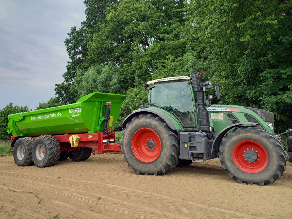 Moderner Traktor mit Anh&auml;nger bei landwirtschaftlichen Lohnarbeiten